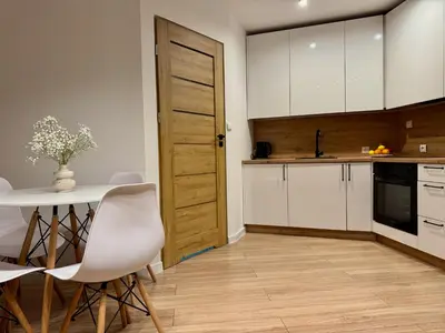 a kitchen with white cabinets and a table and chairs at Zinc FAM in Oświęcim