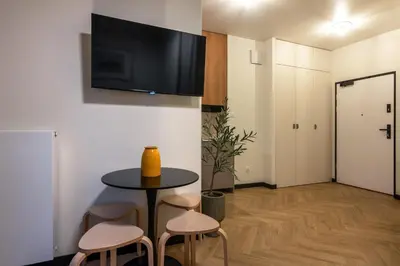 a room with a table and stools and a tv on the wall at WLB Apartments Comfort in Kraków