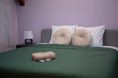 a bed with two pillows and a green comforter at Apartament Solny Loretańska in Kraków