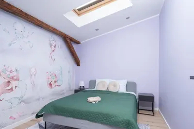 a bedroom with a green bed and a wall with drawings at Apartament Solny Loretańska in Kraków