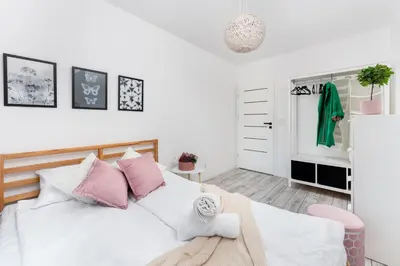 a bedroom with a bed with pink and white pillows at Malila Premium Apartments Cracow Konopnickiej 63E in Kraków