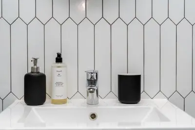 a bathroom sink with two bottles on top of it at Malila Premium Apartments Cracow Konopnickiej 63E in Kraków
