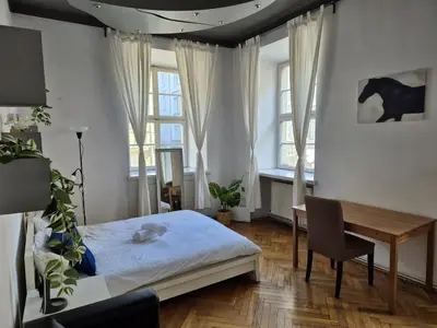 a bedroom with a bed and a desk and windows at Enios Apartments ul Św Tomasza 33 in Kraków