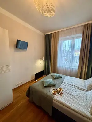 a bedroom with a large bed with a chandelier at Vintage Krowoderska Apartment in Kraków