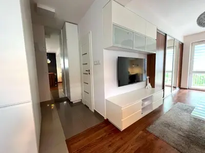 a living room with white cabinets and a television at Aspen Studio in Kraków