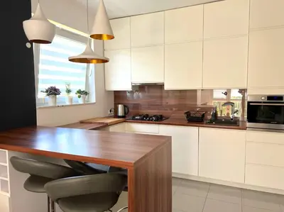 a kitchen with white cabinets and a wooden table at Aspen Studio in Kraków