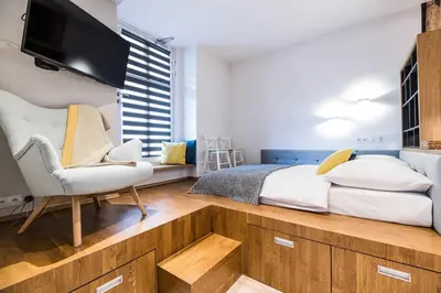 a bedroom with a bed and a chair and a tv at Saguaro Deluxe Apartment Old Town Cracow in Kraków