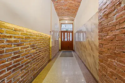 a hallway with a brick wall and a wooden door at Miodowa Heart of Cracow Apartment by BookingHost in Kraków