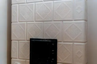 a white tiled wall with a black object on it at Miodowa Heart of Cracow Apartment by BookingHost in Kraków