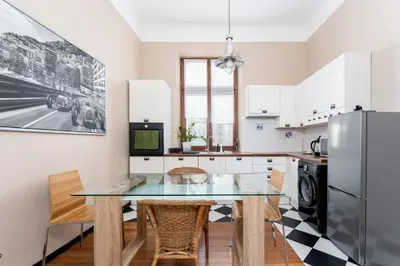 a kitchen with a table and chairs and a refrigerator at Miodowa Heart of Cracow Apartment by BookingHost in Kraków