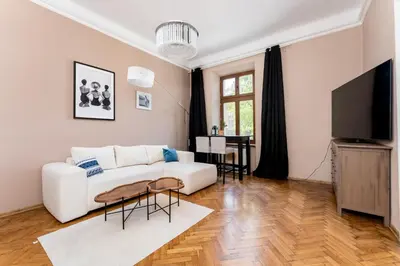 a living room with a white couch and a tv at Miodowa Heart of Cracow Apartment by BookingHost in Kraków