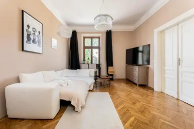 a living room with a white couch and a tv at Miodowa Heart of Cracow Apartment by BookingHost in Kraków
