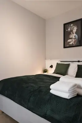a bedroom with a large bed with a green blanket at Metropolis Apartments in Kraków