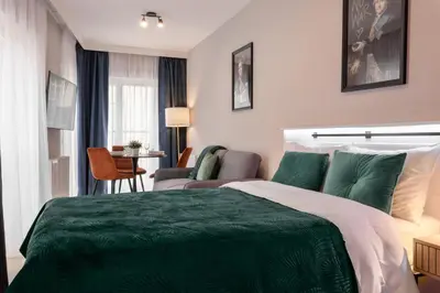 a hotel room with a green bed and a chair at Metropolis Apartments in Kraków