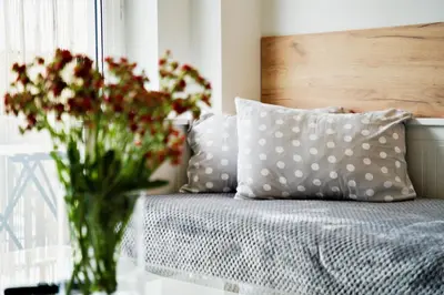 a vase filled with flowers sitting next to a bed at Apartamenty Galicja Zator by Housine in Zator