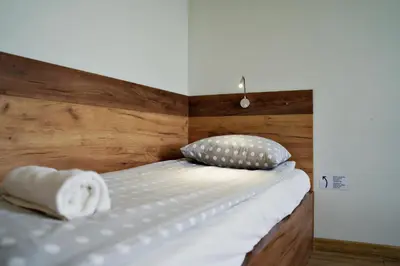 a bed with a wooden headboard and pillows on it at Apartamenty Galicja Zator by Housine in Zator