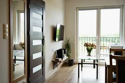a living room with a sliding door and a table with flowers at Apartamenty Galicja Zator by Housine in Zator