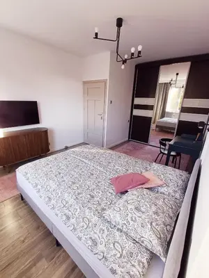 a bedroom with a large bed with a pink pillow on it at Pod Papugami by Meadow Stay Apartments in Kraków