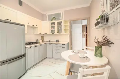 a kitchen with white cabinets and a table and chairs at Pod Papugami by Meadow Stay Apartments in Kraków