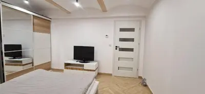 a white room with a bed and a television at Marcel Apartment in Kraków