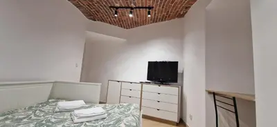 a bedroom with a bed and a tv on a dresser at Marcel Apartment in Kraków
