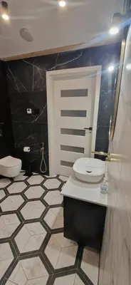 a bathroom with a toilet and a black and white tile floor at Marcel Apartment in Kraków