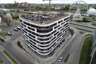 a tall white building with a ferris wheel in a city at Cozy studio next to Cracow Vistula Boulevrads, Old Town in Kraków