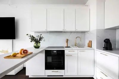 a kitchen with white cabinets and a black microwave at Cozy studio next to Cracow Vistula Boulevrads, Old Town in Kraków