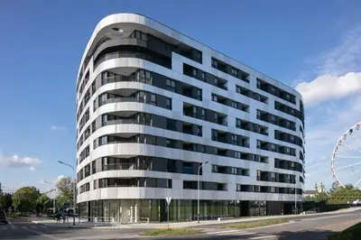 a tall office building with a ferris wheel at Cozy studio next to Cracow Vistula Boulevrads, Old Town in Kraków