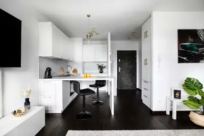 a kitchen with white cabinets and a table and chairs at Cozy studio next to Cracow Vistula Boulevrads, Old Town in Kraków