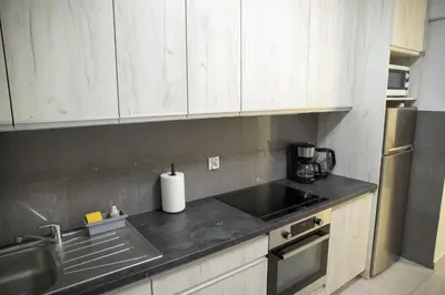 a kitchen with white cabinets and a black counter top at Pradnicka Local Apartment in Kraków