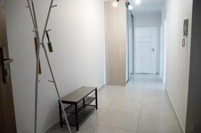 a hallway with a bench and a white wall at Pradnicka Local Apartment in Kraków
