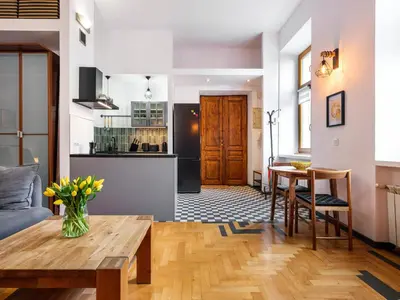 a living room with a table and a kitchen at Podzamcze by Tyzenhauz in Kraków
