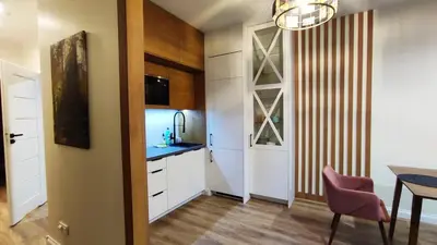 a kitchen with white cabinets and a table and a dining room at Siesta Forest Apartment Relaxing Park in Kraków