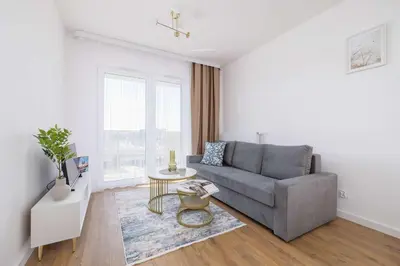 a living room with a couch and a table at Jasny Apartament z Umeblowanym Balkonem w Krakowie Blisko Stawu by Noclegi Renters in Kraków