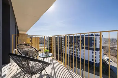 a balcony with two chairs and a building at Jasny Apartament z Umeblowanym Balkonem w Krakowie Blisko Stawu by Noclegi Renters in Kraków