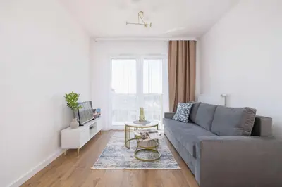 a living room with a gray couch and a table at Jasny Apartament z Umeblowanym Balkonem w Krakowie Blisko Stawu by Noclegi Renters in Kraków