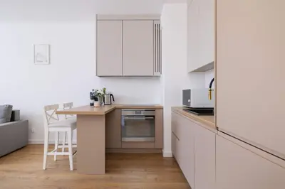 a kitchen with white cabinets and a small wooden table at Jasny Apartament z Umeblowanym Balkonem w Krakowie Blisko Stawu by Noclegi Renters in Kraków