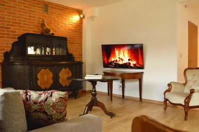 a living room with a fireplace and a tv at Gorczańskie Apartamenty Papiernia - Noclegi w górach Gorce in Niedźwiedź