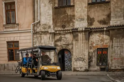 two people riding a golf cart in front of a building at Cracow Route #1 - Old Town in Kraków