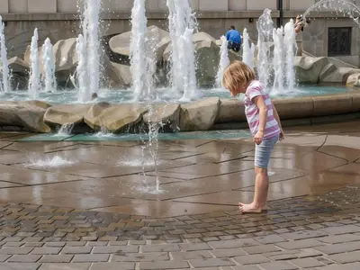 a little girl standing in front of a fountain at Cracow Route #2 - Old Town in Kraków