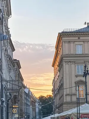 a city street with buildings and a sunset in the background at Cracow Route #4 - Old Town in Kraków