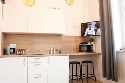 a kitchen with white cabinets and a tv on the wall at Cracow Vistula Boulevard #2 - Old Town in Kraków