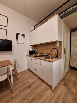 a kitchen with white cabinets and a sink and a table at Cracow Vistula Boulevard #3 - Old Town in Kraków