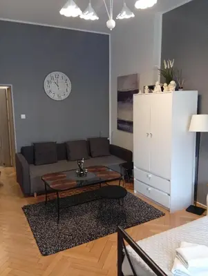 a living room with a couch and a clock on the wall at Pod Topola in Kraków