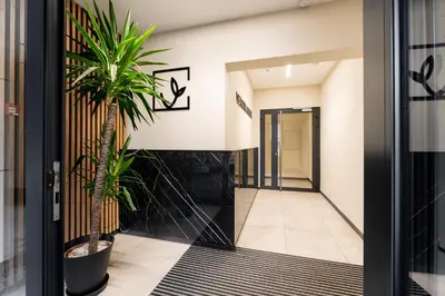 a hallway with a palm tree in front of a door at Malila Premium Apartments Cracow Plac Bohaterów Getta in Kraków