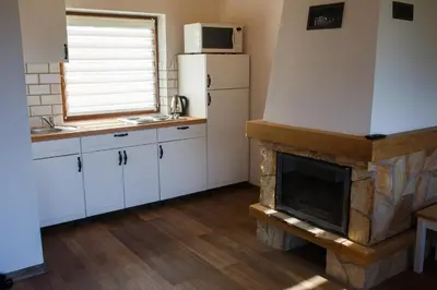 a kitchen with a fireplace and a refrigerator at Lawendowy Domek in Jaszczurowa