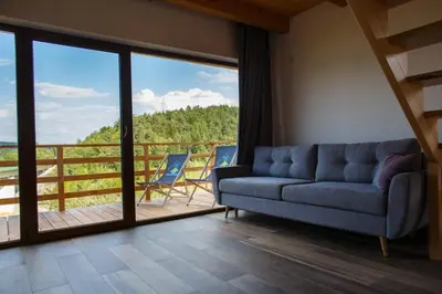 a living room with a couch and a balcony at Lawendowy Domek in Jaszczurowa