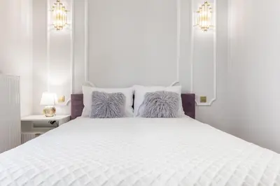 a white bedroom with a large white bed with pillows at Exclusive Panoramic APARTMENT in Kraków