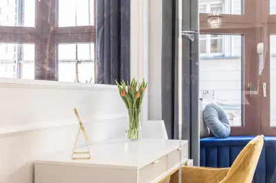 a white desk with a vase of flowers on it at Exclusive Panoramic APARTMENT in Kraków